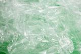 Background texture of crumpled green plastic sheeting reflecting light in a close up full frame view