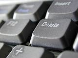 Extreme close up on delete key in focus on gray colored computer keyboard with pause and insert out of focus