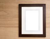 Empty wooden frame with mount card hanging on a wood panelled wall with copy space in the center for your artwork