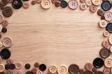 Fashion frame of assorted brown toned buttons on a wooden background with copy space viewed from above