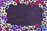 Colorful heart frame with decorative cut out heart shapes on wood with central copy space for your romantic message of love