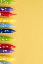 Colorful party candle border on a yellow background with copy space with the tips and wicks of the unused candles arranged to the side in a line
