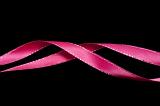 Twirled pink ribbon festive border on a dark background with copy space above and below for your greeting