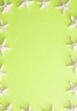Small white starfish border on a colorful lime green background for summer vacation, nautical or marine concepts