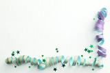 Streamers corner border party background with spiral coiled green and purple ribbons and scattered stars over white with copy space for your seasonal holiday or birthday greeting