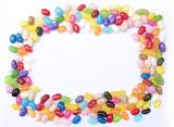 Colorful jujube or jelly bean frame with brightly colored candy in the colors of the rainbow on white with central copy space