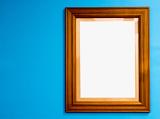 Empty wooden frame for your artwork or photo on a blue background with copy space alongside