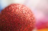 Close Up of Red Glitter Christmas Ornament Ball in Diffuse Focus with Colorful Background and Copy Space