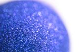 Decorative blue glitter ball or Christmas bauble viewed close up with shallow DOF over white with copy space