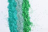 Colorful green craft glitter in three different shades in parallel lines on white with copy space, overhead view