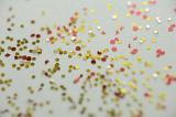Concept Abstract Background of Gold and Red Celebratory Glitter Scattered Across White Background in Selective Focus