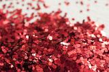 Close up view on pile of bright red circular sparkling glitter objects with background out of focus