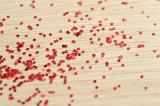 Scattered glittering red sequins on a wooden background for a festive or party concept with shallow DOF