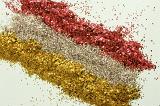 Gold and red glitter pattern with three lines of yellow and rose gold and red at a diagonal angle on a white background, high angle view for Christmas or festive occasions