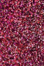 Colorful red glitter background texture with a mix of red, silver and pink craft glitter in a full frame view for party or holiday concepts