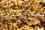 A background of golden glitter sprinkles pictured in narrow depth of field with copy space in the foreground and rear