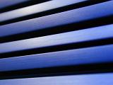 Background composed of blue blinds taken in an extreme close up view with black spaces in between