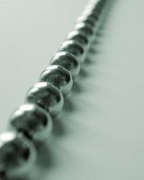 Unusual background with close up view of metal balls strung together against a light colored table