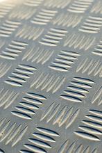 Conceptual background with close up view of indented metal with checkered pattern with rows of four lines each