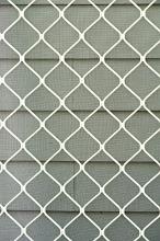 Conceptual background of patterned white fence beside green siding on a clear day