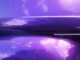 Reflection of sky and clouds in smooth purple curved surface as full frame background with copy space