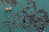 Top down close up view on resistors and other electronic parts on green colored printed circuit board