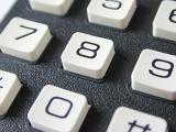 Macro shot of the white numerical keys or buttons on a keypad with a textured dark grey surface