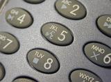 Top down angled close up on oval shaped telephone keypad with media control symbols