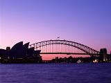 Spectacular deep purple sunset of Sydney harbour silhouetting the Opera House and bridge against a fiery pink glow