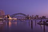 Purple sunset over Sydney Harbour Bridge, Australia on a tranquil summer evening with boat traffic and city lights in a transport and travel concept