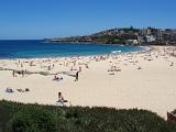 Scenic view on a hot summer day of the golden sands of Coogie Beach, Sydney, Australia dotted with sun worshippers and tourists and a calm blue ocean with no surfers