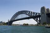 Low angle view of Sydney Harbour Bridge, Australia, with the steel arch silhouetted against a clear sunny blue sky taken at water level