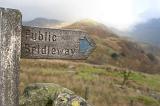 Rustic wooden arrow showing the right direction towards the public bridleway, in a wild mountainous area