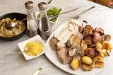 Chicken roast carved and displayed on a plate with golden roast potatoes and individual side servings of vegetables