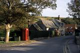 Picturesque street in Lulworth Village with an iconic red public telephone booth and quaint English cottages