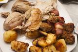 Roast dinner ready for serving on a plate with carved chicken or turkey accompanied by golden roast potatoes, close up view