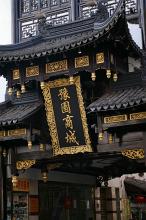 Black Chinese temple with intricate gold leaf decoration and calligraphy adorning the facade, close up detail view