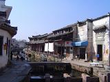 Daily Life on Urban Street with Canal Through Residential Area in Urban China on Sunny Day with Clear Blue Sky