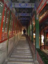 Rear View Silhouette of People Ascending Covered Staircase Walk Way in Traditional Chinese Temple with Colorful and Intricately Carved Wooden Beams