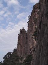 Scenic of Huangshan Yellow Mountain Range - Low Angle View of Steep Huangshan Cliff with Trees Framed by Blue Sky with White Clouds in Anhui Province, China