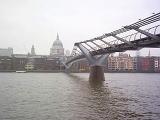 Low angle view from the water of the Millennium Bridge, London, crossing the River Thames with St Paul's Cathedral in the background on an overcast day