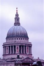 The domed roof of St Pauls Cathedral, London, at twilight lit by a lilac light against an overcast sky
