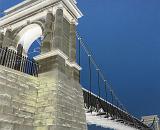 Stone support tower on a suspension bridge viewed from below looking up against a blue sky