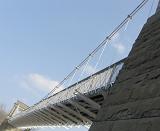 Oblique angle view of the cables and towers of a suspension bridge viewed from below against a blue sky