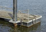 Large floating pontoon jetty or pier showing the end pole support and mooring ropes for boats