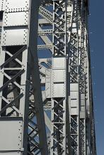 Detail of tall steel bridge trusses against a blue sky in an engineering and architectural concept