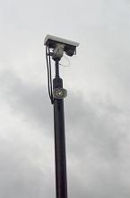 CCTV security cameras mounted on a tall pole for the surveillance of the surrounding area against a cloudy grey sky