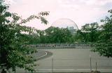 Montreal Biosphere dome museum viewed from distance with lots of green foliage and city park in foreground. Quebec, Canada