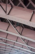 Massive metal beams and trusses of a bridge structure, viewed from low angle in close-up