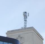 Transmitter aerial on top of a flat roofed building viewed from below in a communications concept